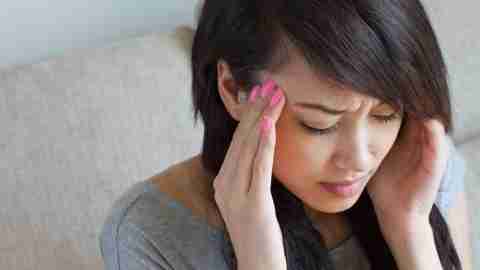 A woman holds her head, wishing she could stop her OCD symptoms.
