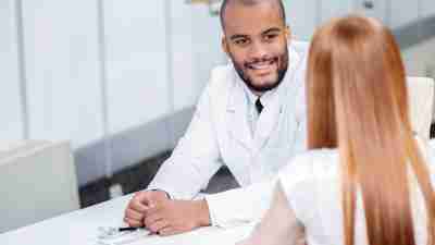A doctor evaluates his patient for ADHD by talking with her. Diagnosis requires more than just brain imaging.