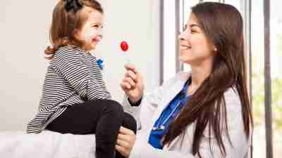 Pediatrician giving a lollipop to a little girl at her office after evaluating for Tourette Syndrome and sharing some basic facts.