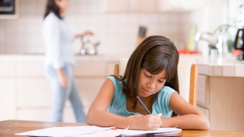 A student completes her assignment while making sure to organize to avoid losing completed work and homework stress.