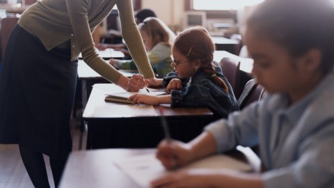 A teacher explains a concept in depth to a student in school helping to relieve homework stress at home.