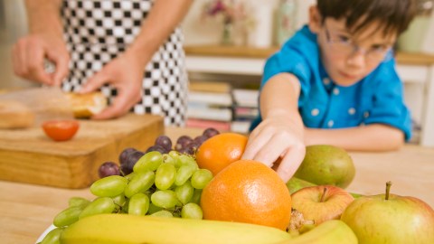 A boy with ADHD reaches for a piece of fruit.