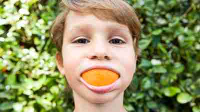 ADHD boy has an orange in his mouth.