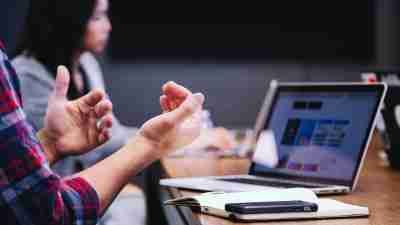 A woman and a man sit at a desk and discuss how to be more productive with ADHD at work.