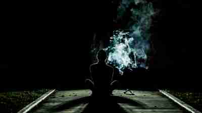 A teen sitting on the track, smoking