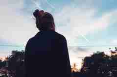 The silhouette of a ADHD woman looking at sunset in the distance.